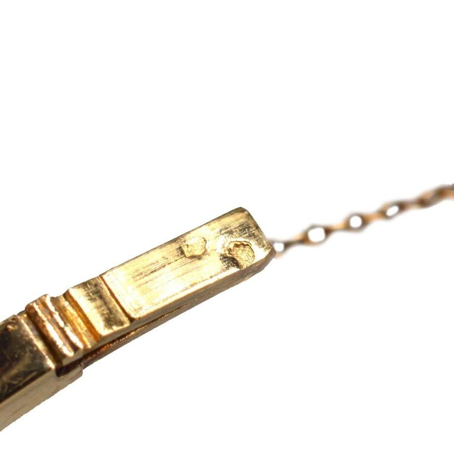 Close-up of the clasp of a vintage gold jewelry piece with intricate detailing.
