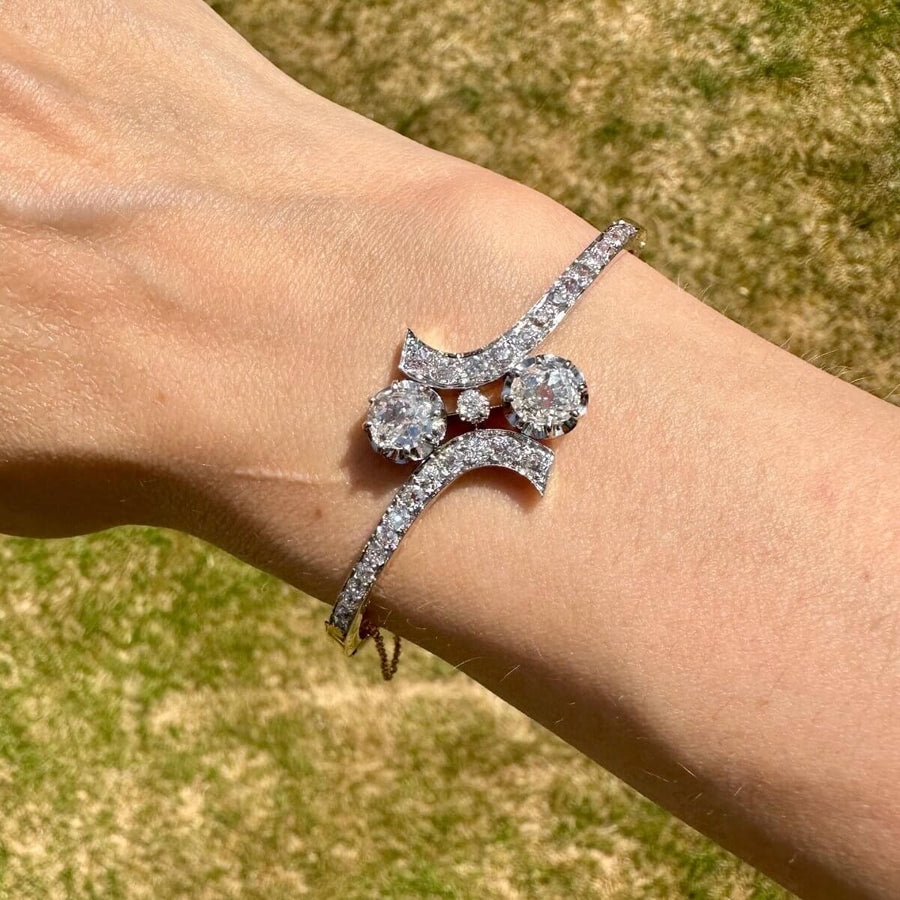 French early 20th century 18ct gold and platinum Toi et Moi diamond bangle on wrist in sunlight.
